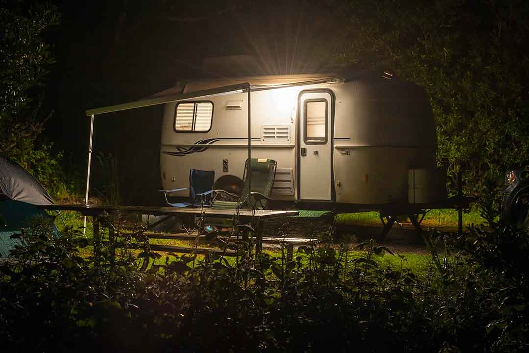 A RV trailer parked and people camping out at night