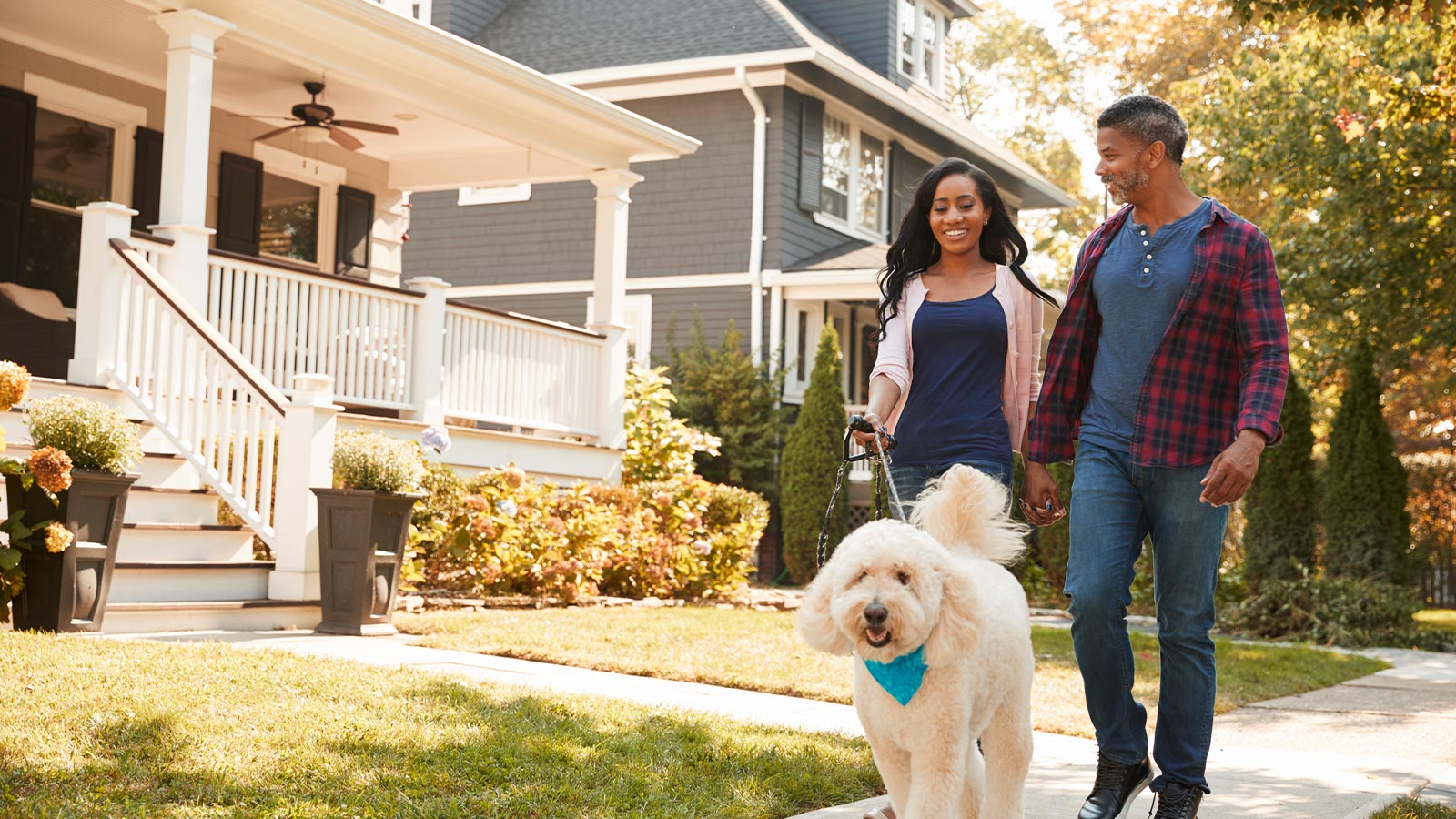 a happy couple walking their dog in their neighborhood