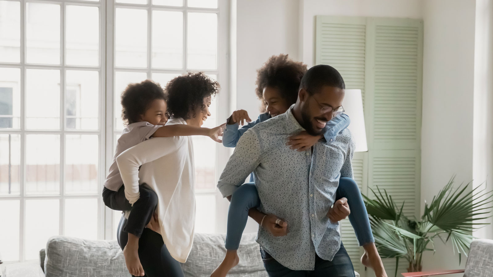 children playing on the backs of their parents inside of their home