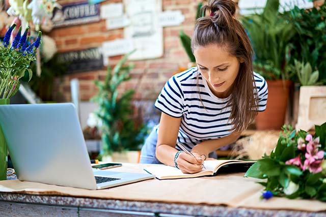 A young female entrepreneur taking notes from her computer